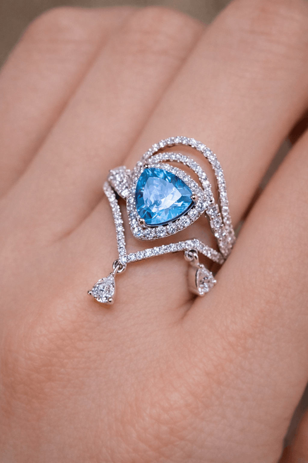 Trillion-cut apatite ring with halo setting and diamond-accented draped design
