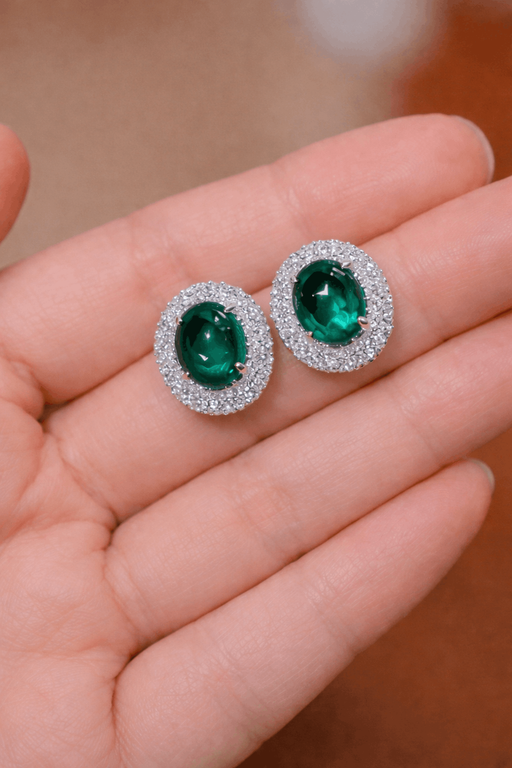 Pair of oval lab emerald stud earrings with double halo setting
