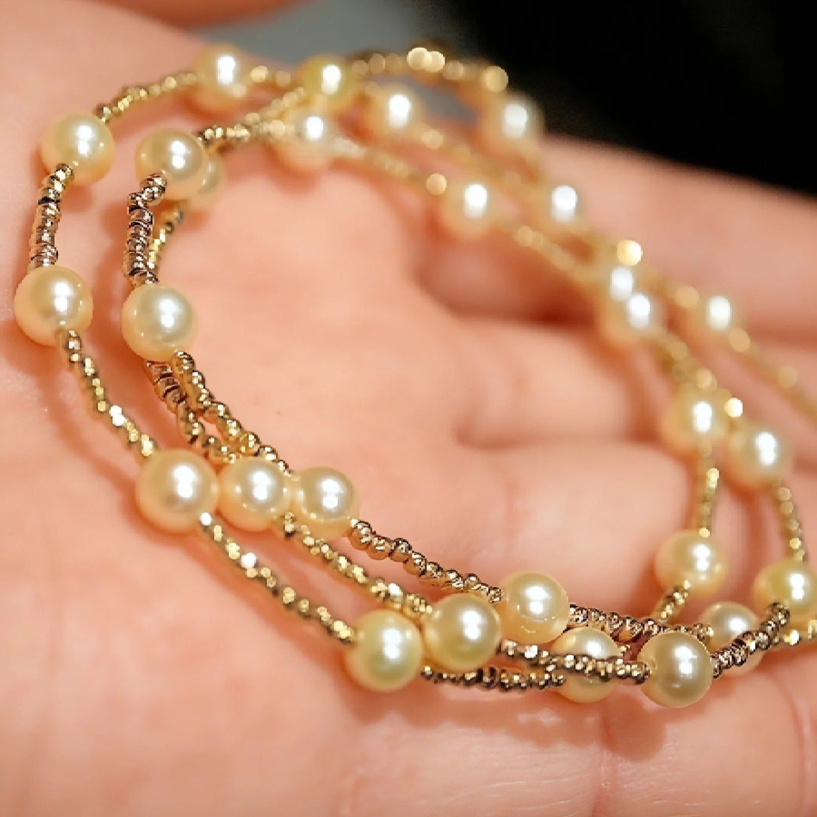 Pearl and gold beaded layered necklace in hand
