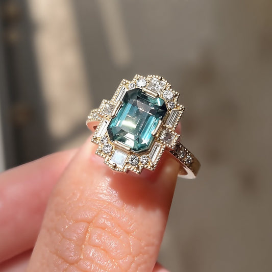 Vintage teal sapphire ring with lab-grown diamond halo in gold setting








