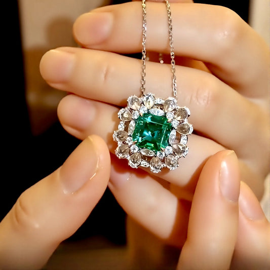 Elegant pendant with 3ct lab-grown emerald and halo of rose cut diamonds held in hand
