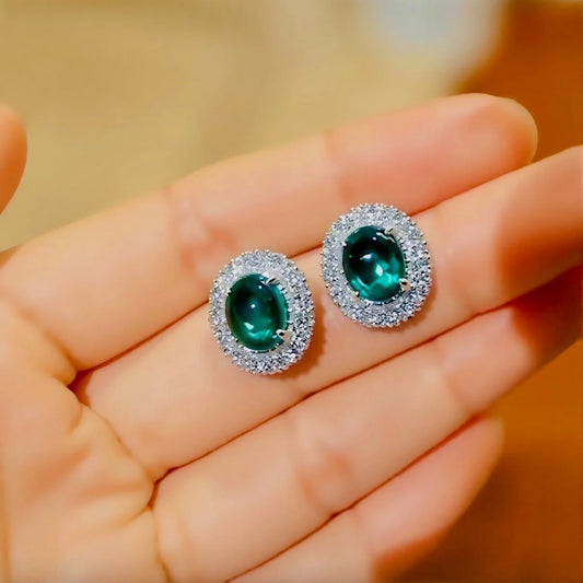 Pair of oval lab emerald stud earrings with double halo setting
