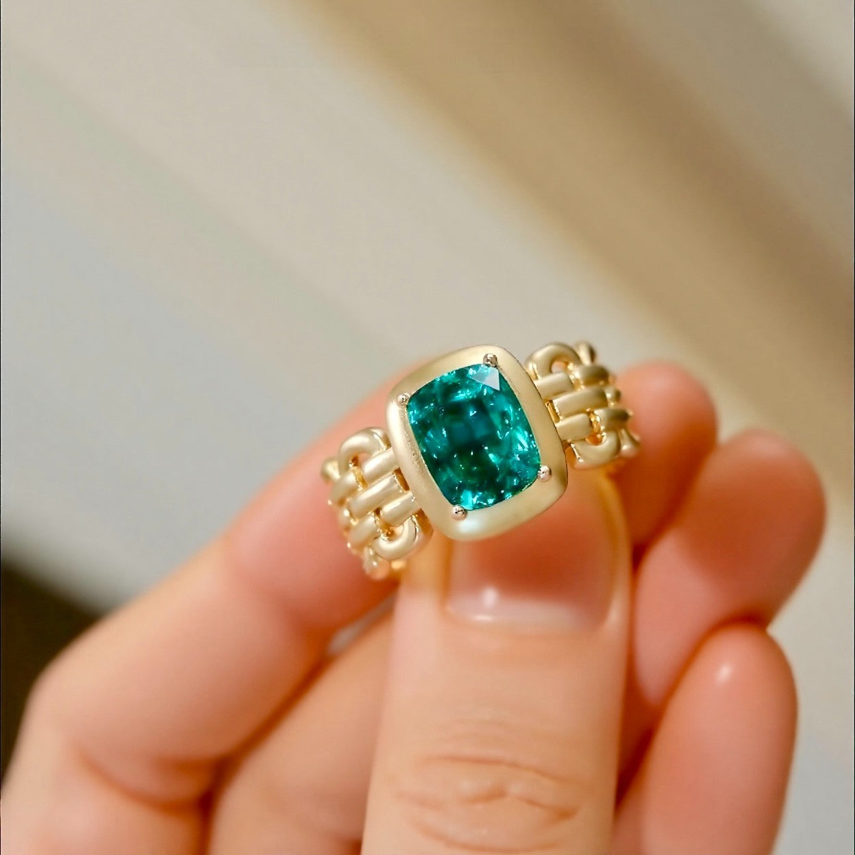 Avarelle ring featuring 3ct cushion cut lab grown emerald in matte gold bezel and linked gold band








