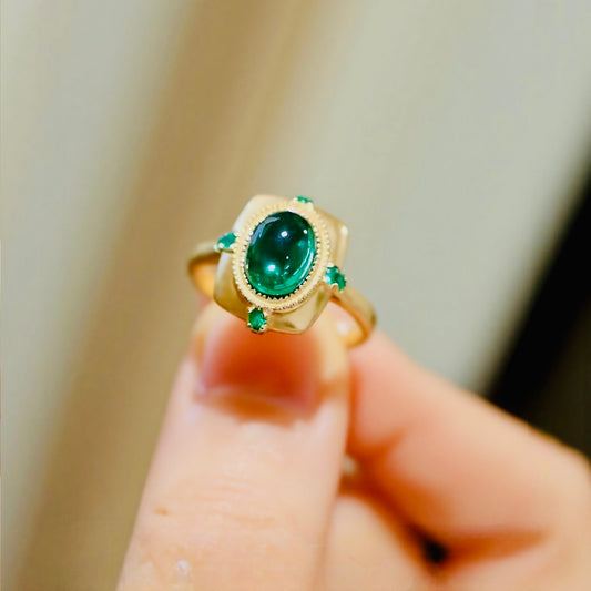 Matte gold ring with 2ct lab-grown cabochon emerald and four small emerald accents









