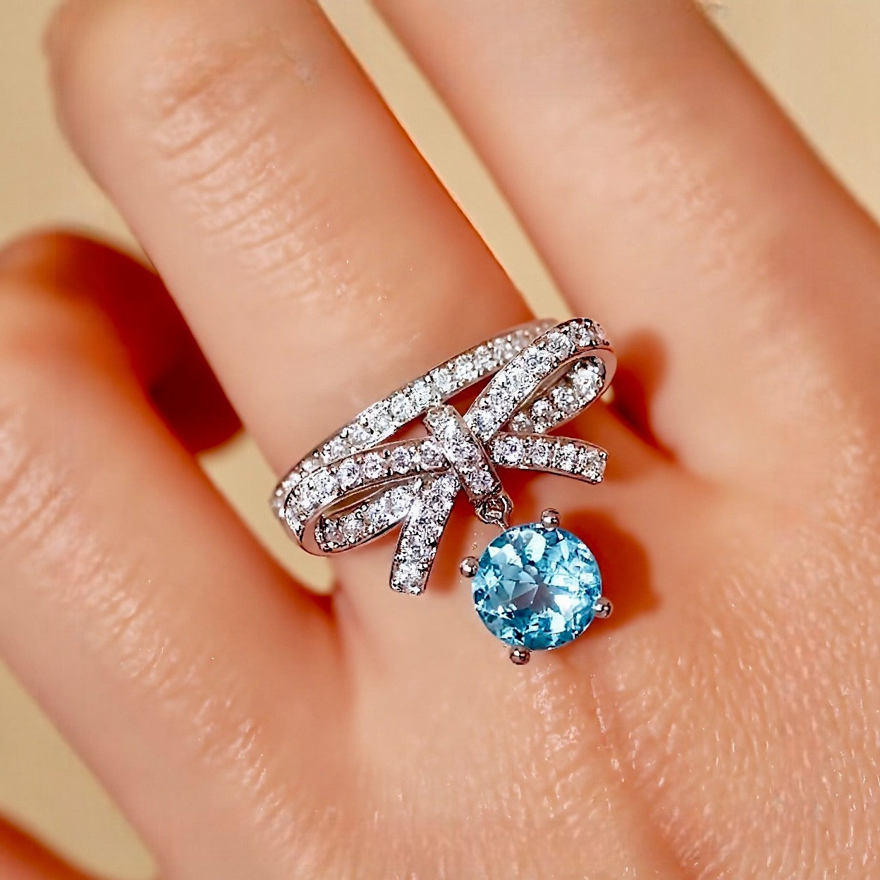 White gold ring with bow design and dangling 1ct lab aquamarine stone








