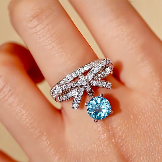 White gold ring with bow design and dangling 1ct lab aquamarine stone








