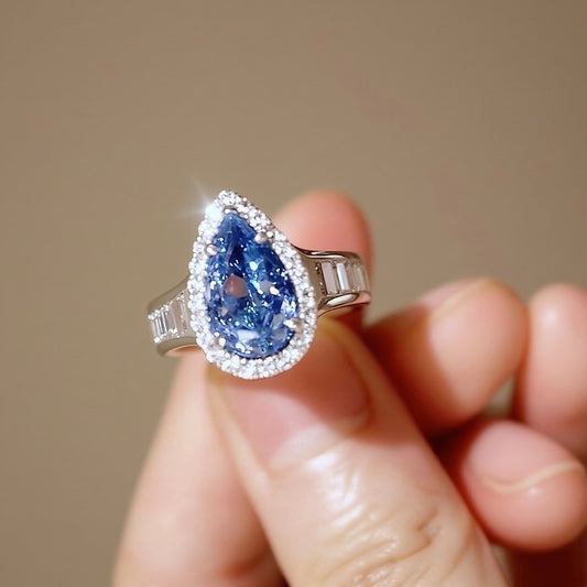 Elegant 4ct lab-grown blue diamond pear ring with white diamond halo and baguette accents in gold








