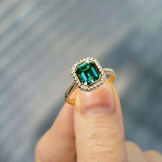 Belline ring with emerald-cut lab-grown emerald and diamond halo in gold setting








