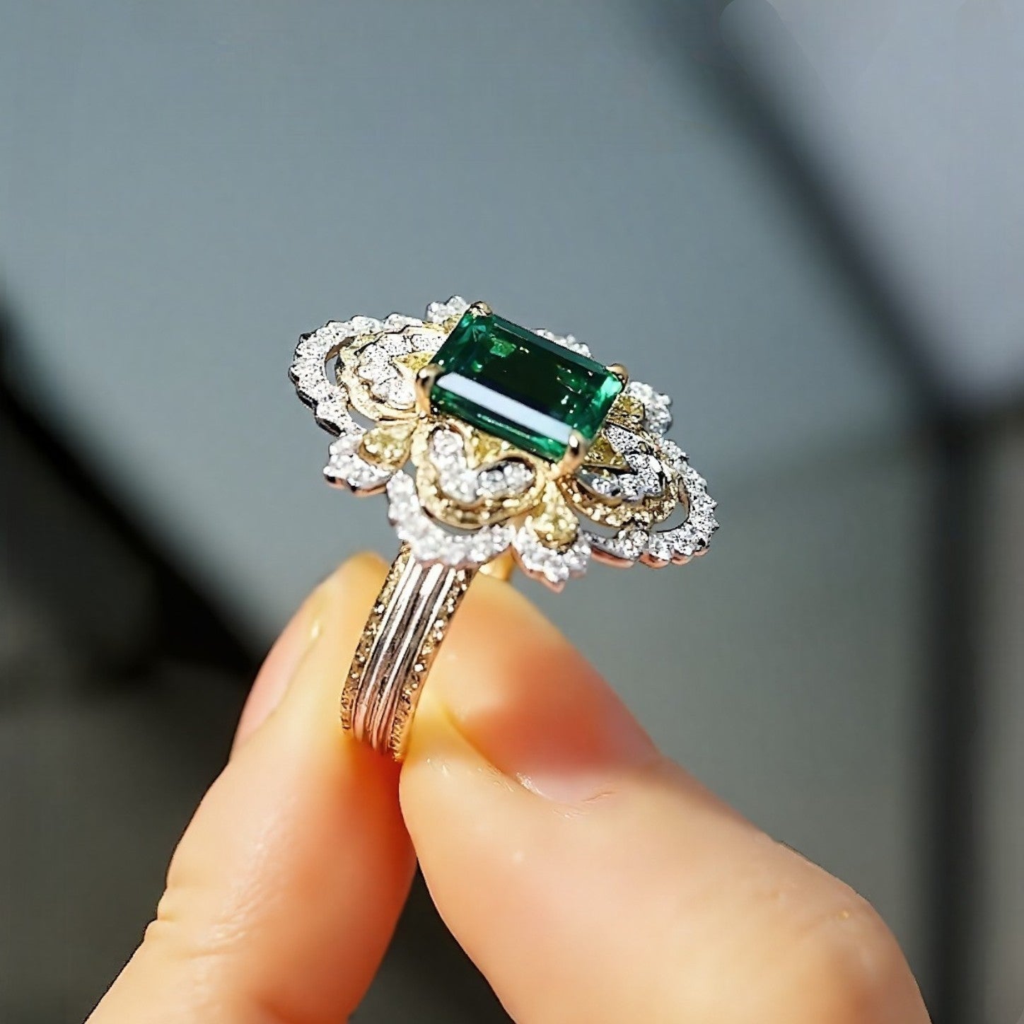 Ornate emerald ring with floral diamond halo and triple gold band