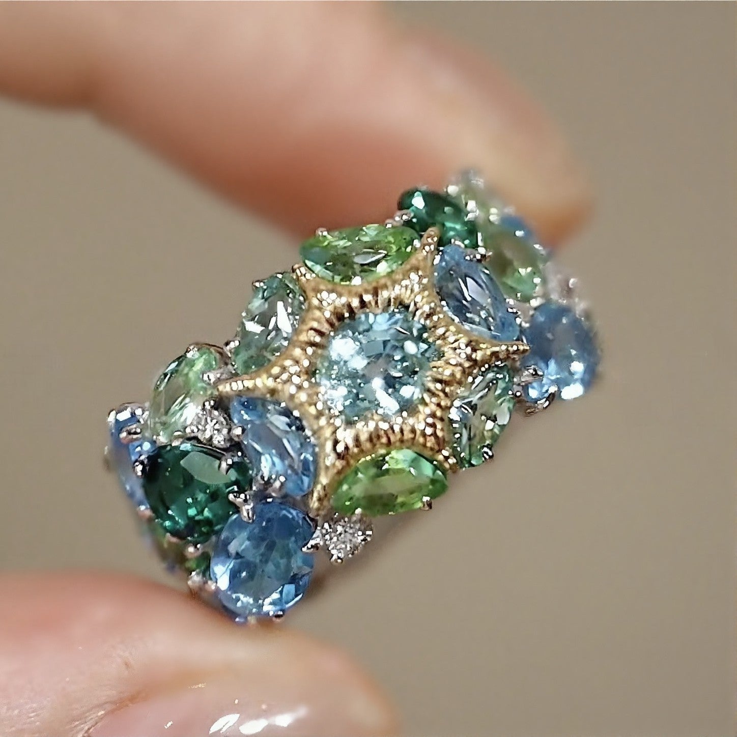 Neravelle ring with tourmaline, tsavorite, and aquamarine gemstones in starburst gold and platinum cluster setting – colorful cocktail band ring design

