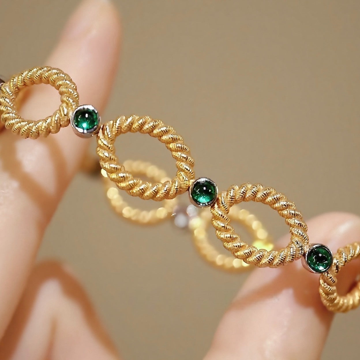 Gold twisted link bracelet with cabochon emerald accents








