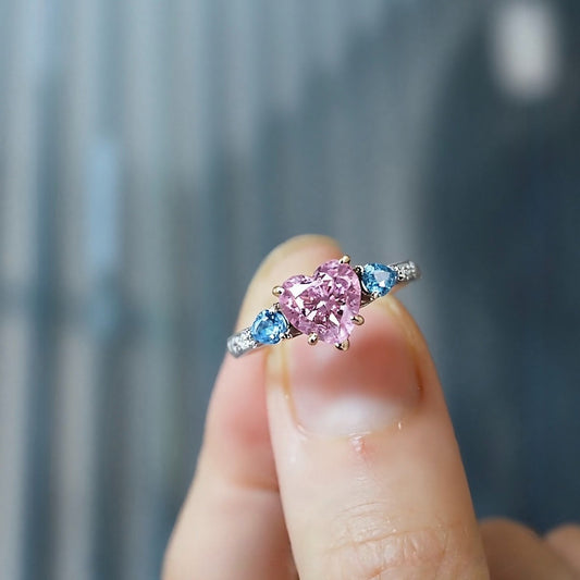 Lab-grown pink heart diamond ring with blue side stones in pavé white gold setting
