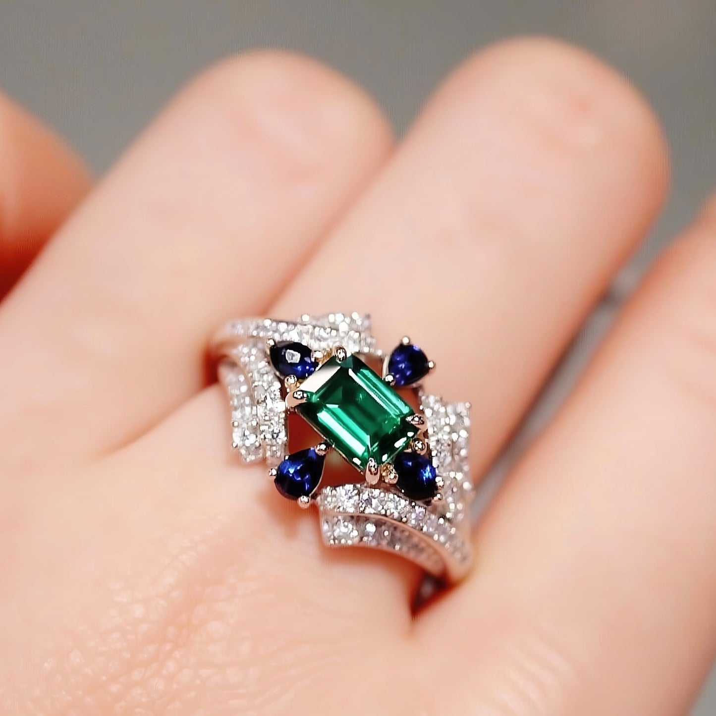 Lab emerald ring with sapphire and diamond halo
