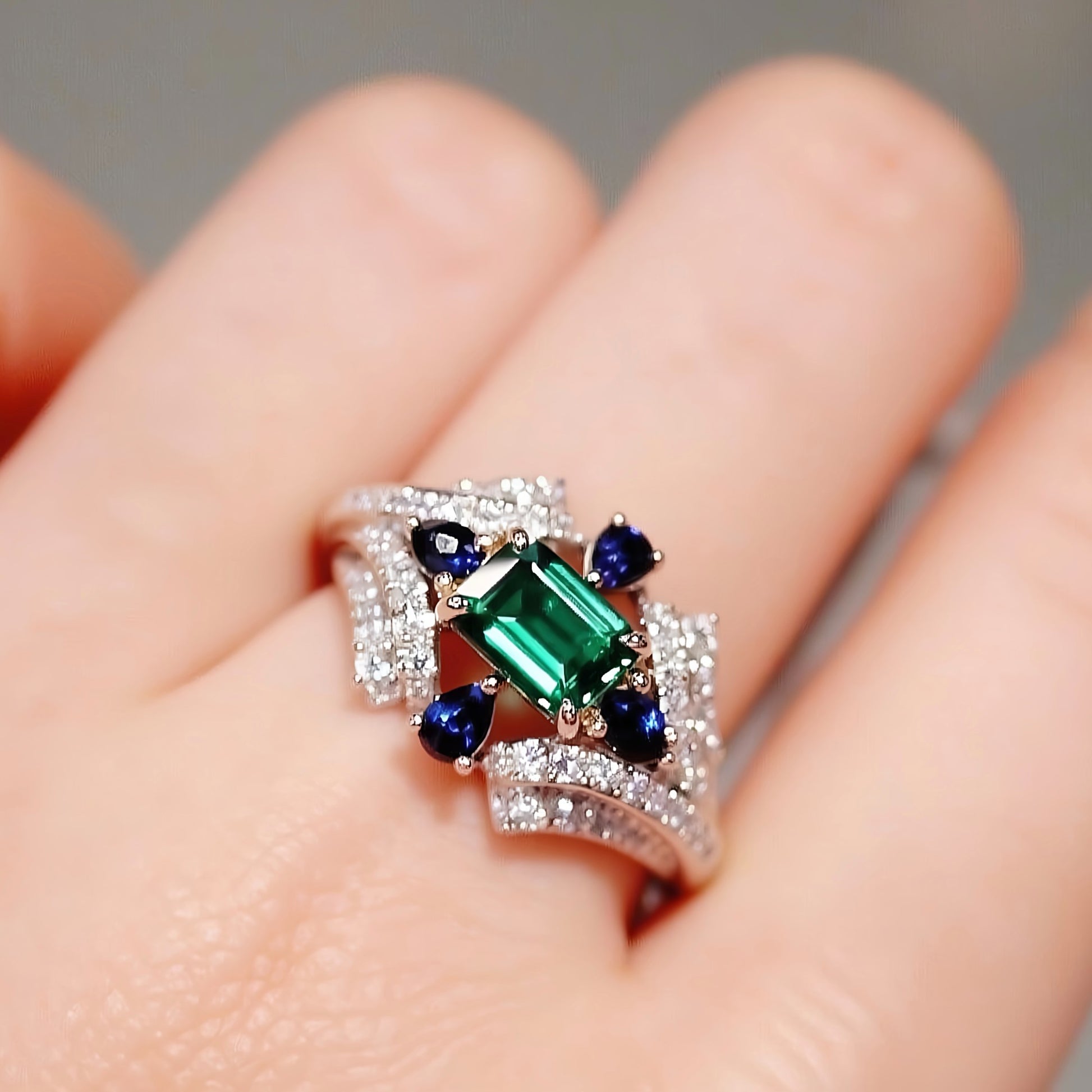 Lab emerald ring with sapphire and diamond halo
