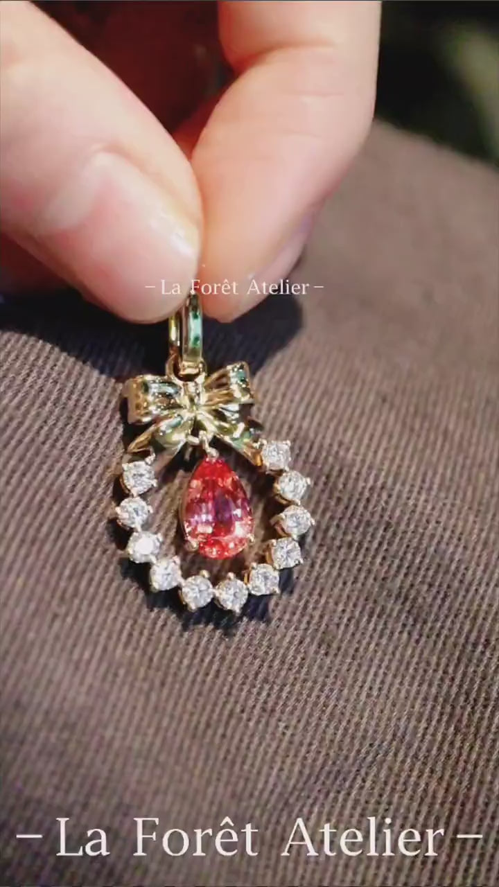 Elegant gold pendant featuring pear-cut lab sapphire and bow