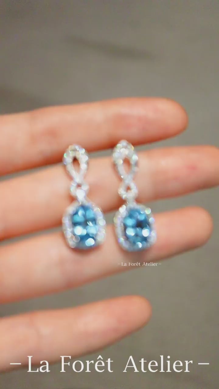 Oval aquamarine drop earrings with diamond halo and twisted white gold design








