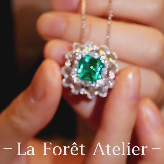 Elegant pendant with 3ct lab-grown emerald and halo of rose cut diamonds held in hand








