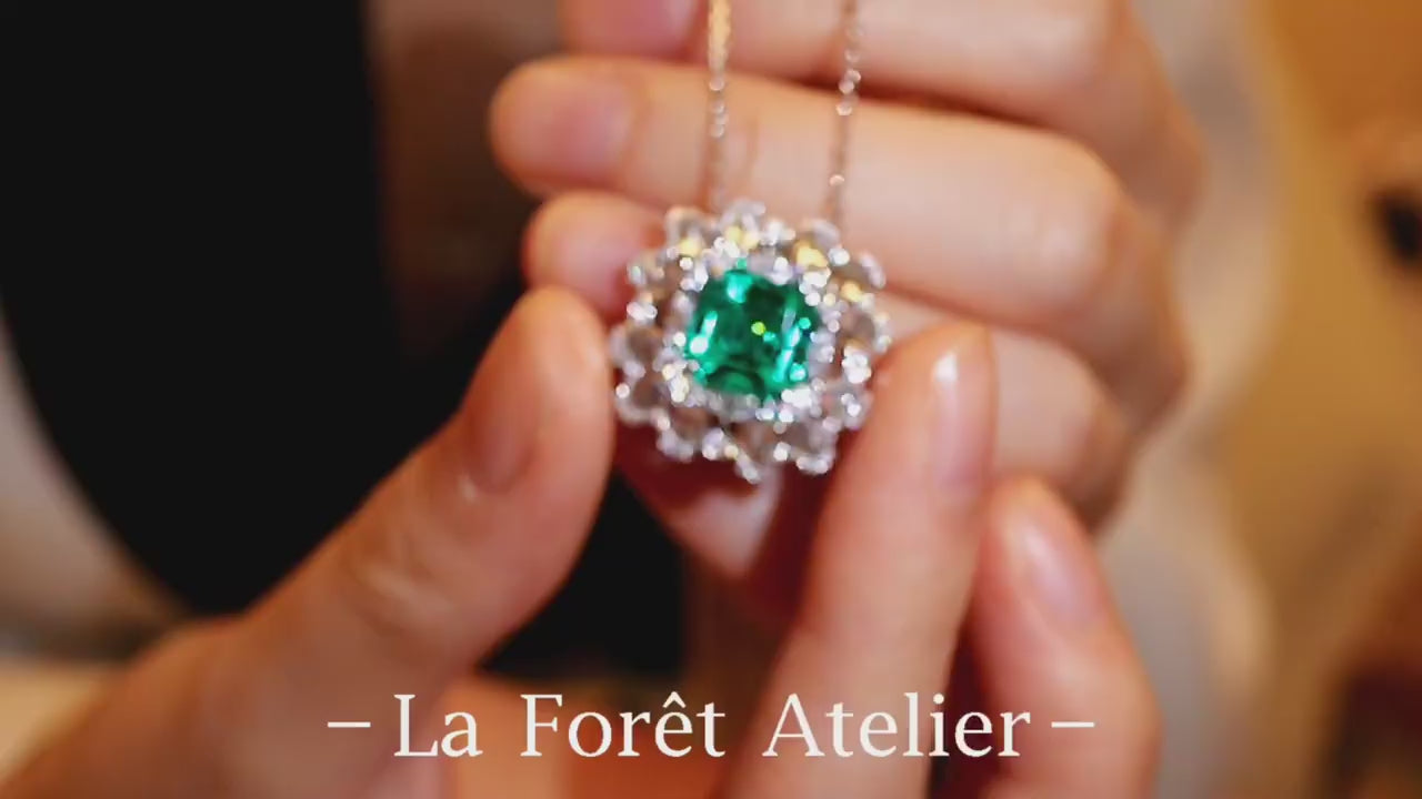 Elegant pendant with 3ct lab-grown emerald and halo of rose cut diamonds held in hand








