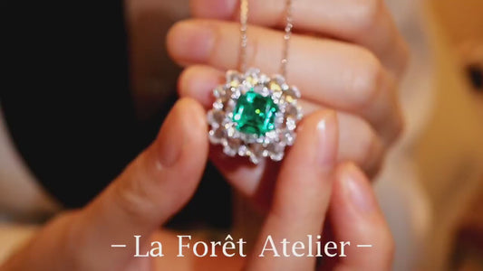 Elegant pendant with 3ct lab-grown emerald and halo of rose cut diamonds held in hand








