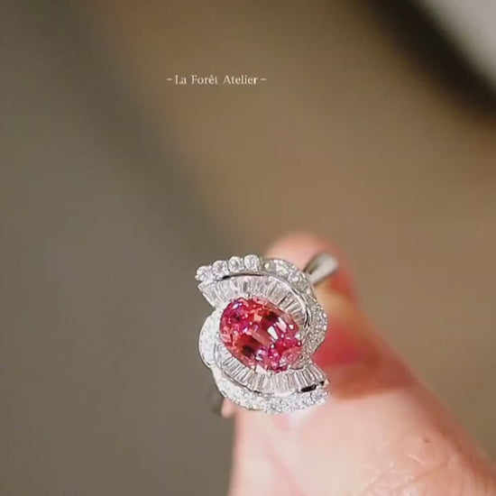Elegant crescent diamond halo ring featuring oval lab pink-orange sapphire