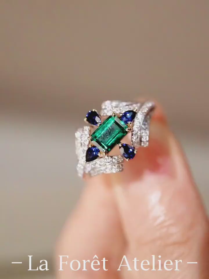 Eirisse lab emerald ring with sapphires and diamonds in white gold setting








