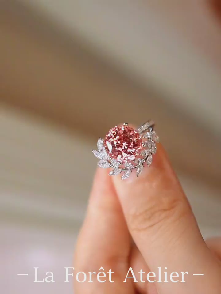 Floral-inspired ring with 4ct padparadscha sapphire in white gold setting surrounded by diamond leaves.