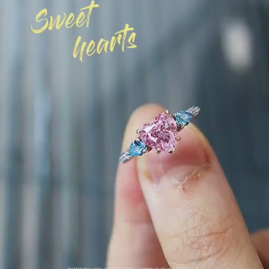 Lab-grown pink heart diamond ring with blue side stones in pavé white gold setting









