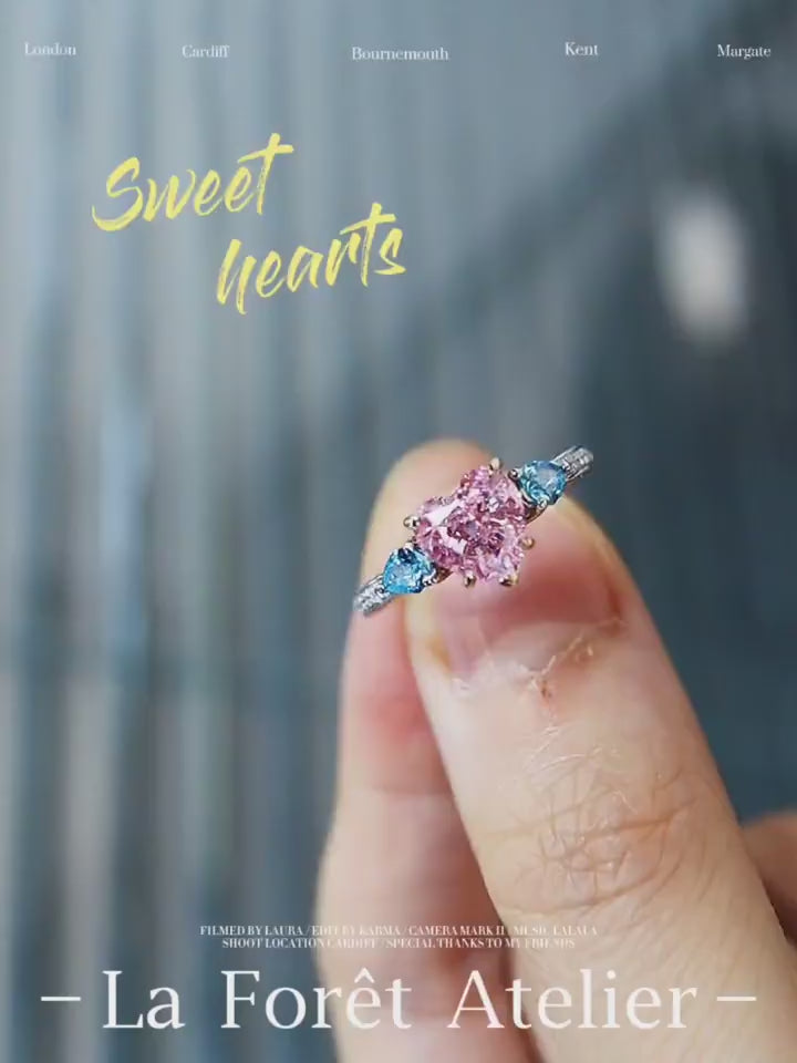 Lab-grown pink heart diamond ring with blue side stones in pavé white gold setting








