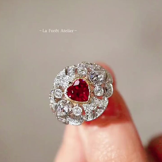 White gold ring with heart-shaped lab ruby and diamond halo in a vintage-inspired design
