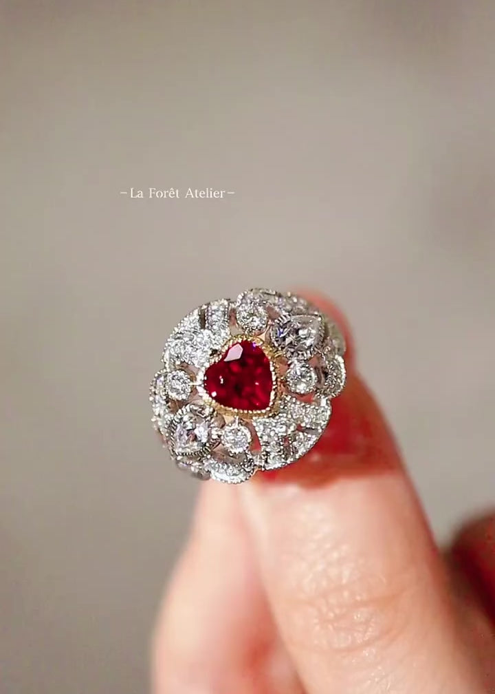 White gold ring with heart-shaped lab ruby and diamond halo in a vintage-inspired design
