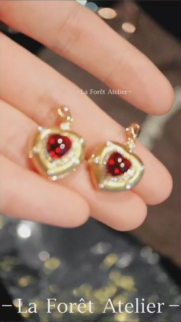 Gold charm necklace featuring heart-cut ruby and star accents