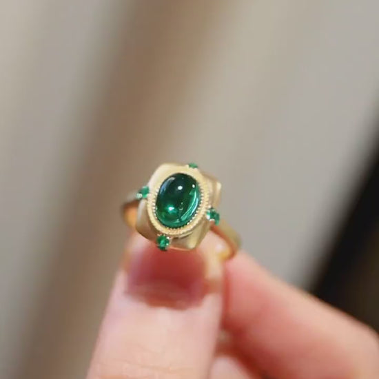 Matte gold ring with 2ct lab-grown cabochon emerald and four small emerald accents








