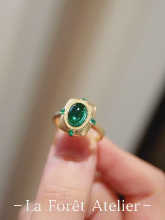 Matte gold ring with 2ct lab-grown cabochon emerald and four small emerald accents








