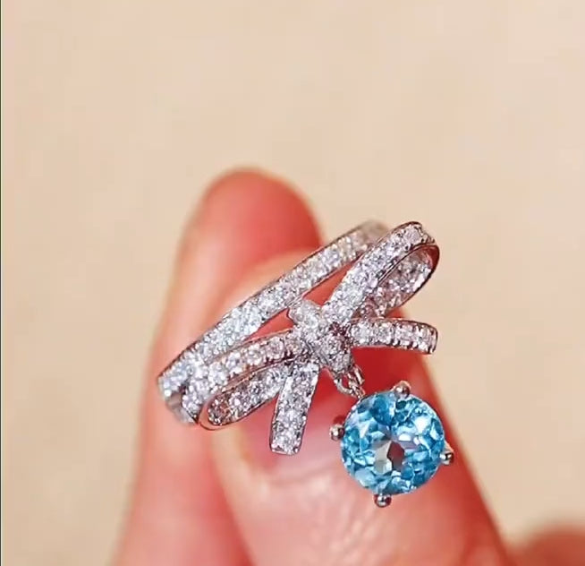 White gold ring with bow design and dangling 1ct lab aquamarine stone








