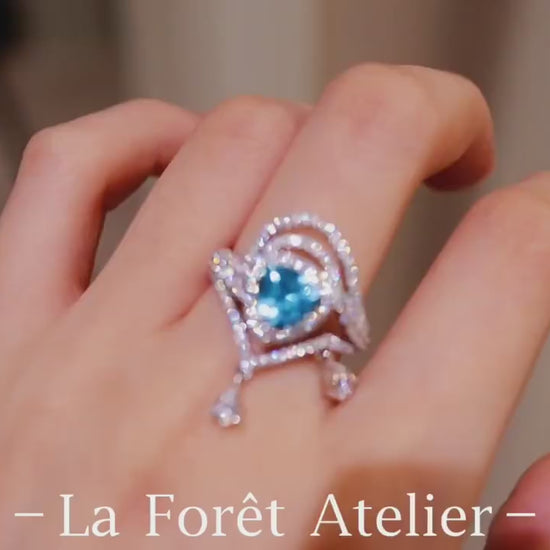 Trillion-cut apatite ring with halo setting and diamond-accented draped design








