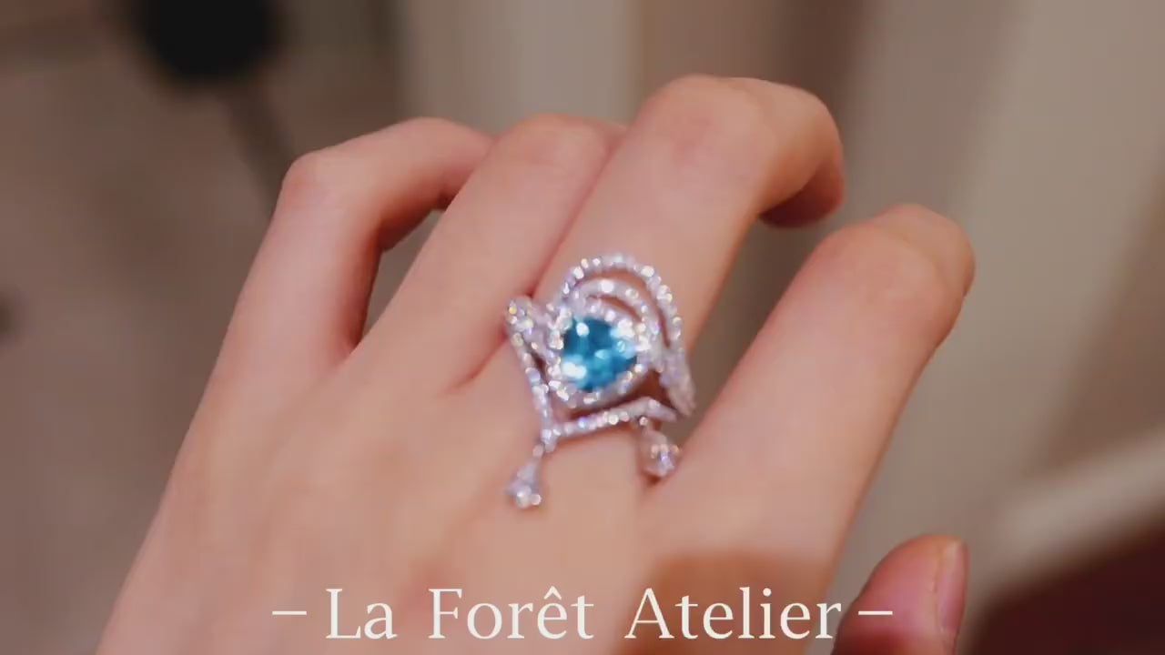 Trillion-cut apatite ring with halo setting and diamond-accented draped design








