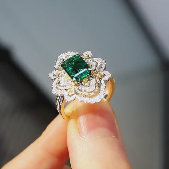 Ornate emerald ring with floral diamond halo and triple gold band
