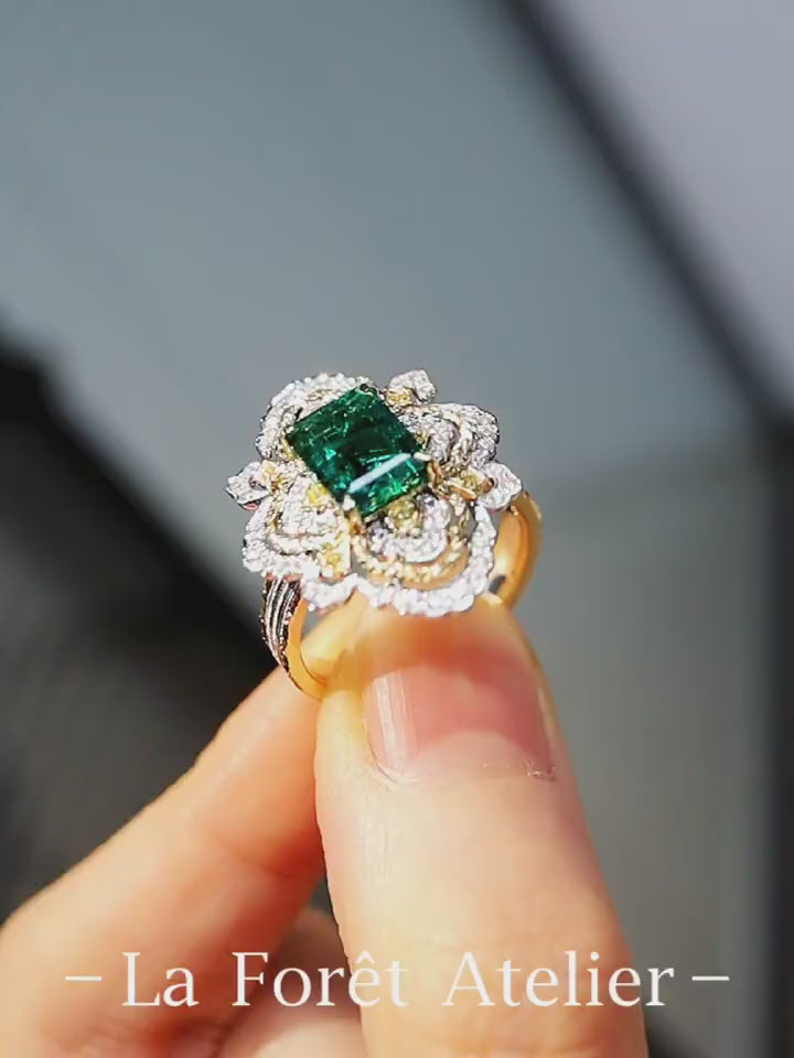 Ornate emerald ring with floral diamond halo and triple gold band